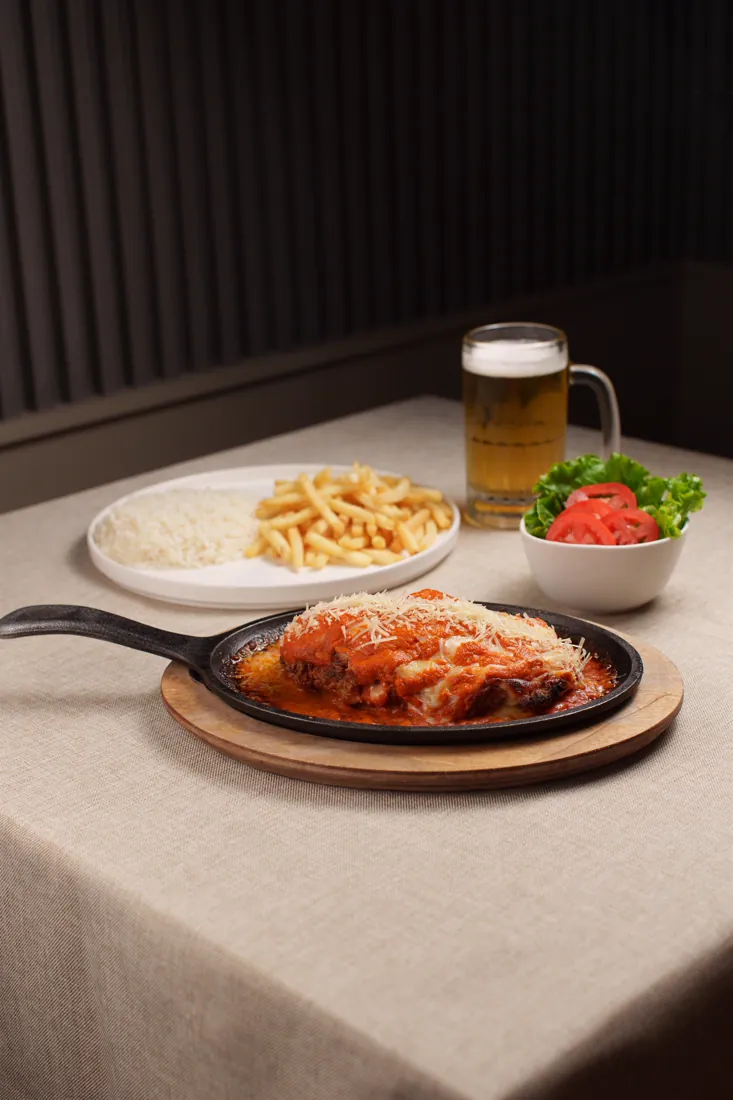Parmegiana na chapa com guarnições
